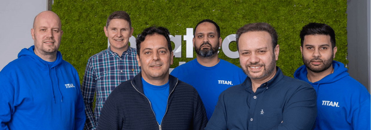 Tariq Muhammad with members of the TITAN PMR team standing in front of an Invatech Health wall, representing support for independent pharmacy owners