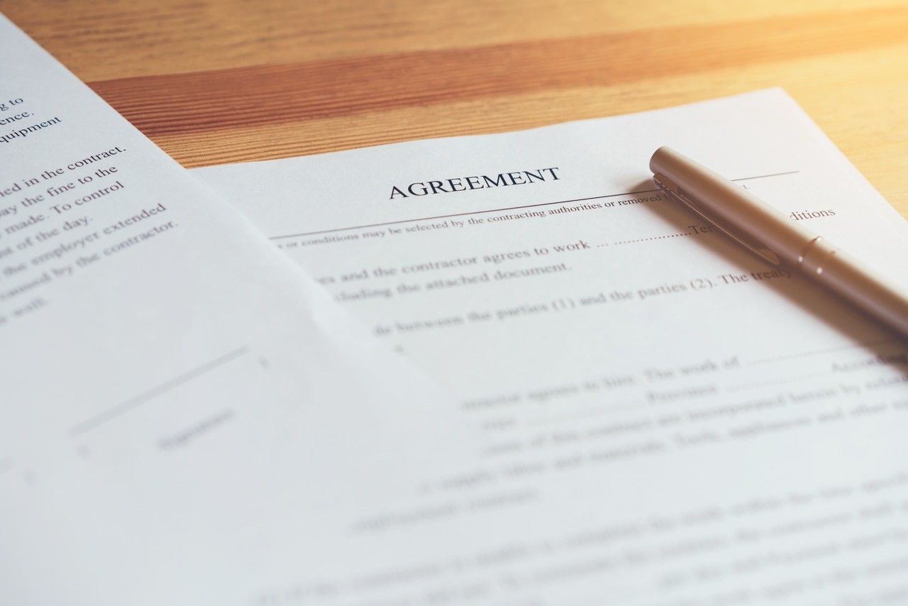 A focused view of a legal agreement document with a pen on top, highlighting SAA Law's expertise in drafting and managing commercial and civil contracts.