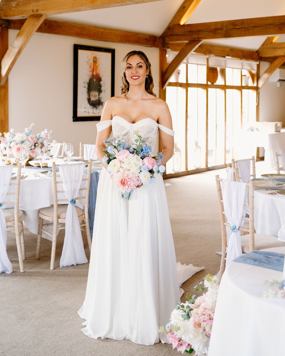 A bride in a white lace wedding dress holds a colorful bouquet of pink, yellow, and orange flowers.