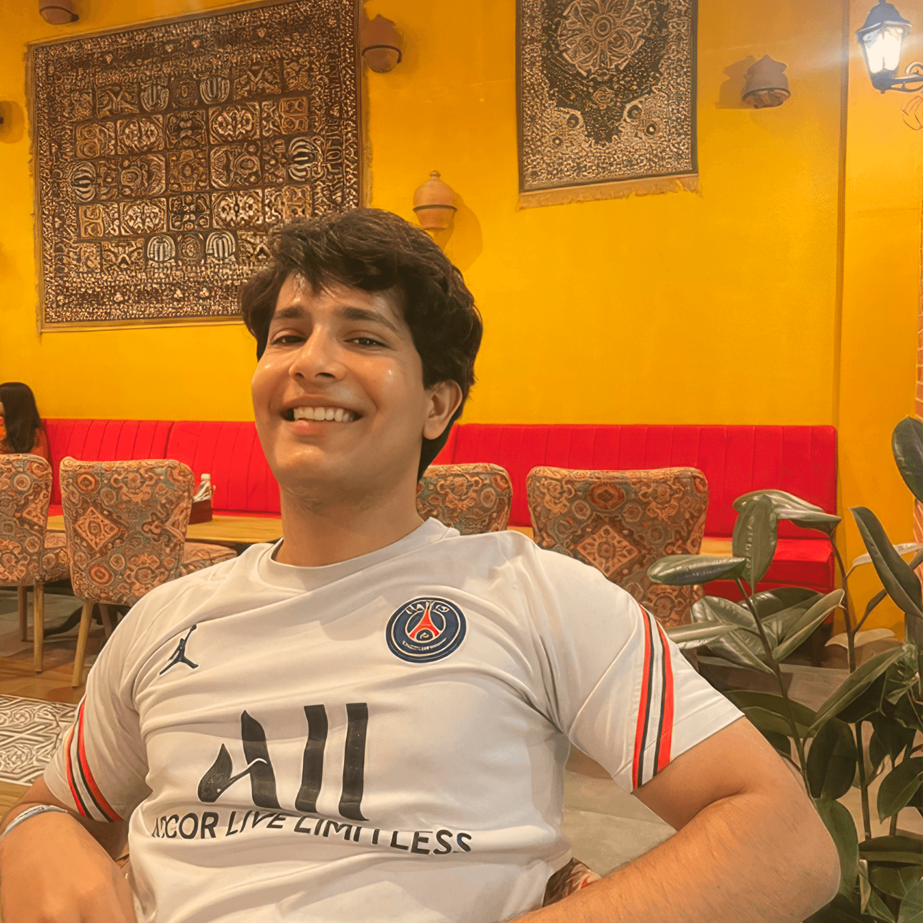 Woman with red hair and sunglasses smiling, wind-blown hair, with hot air balloons in the background.