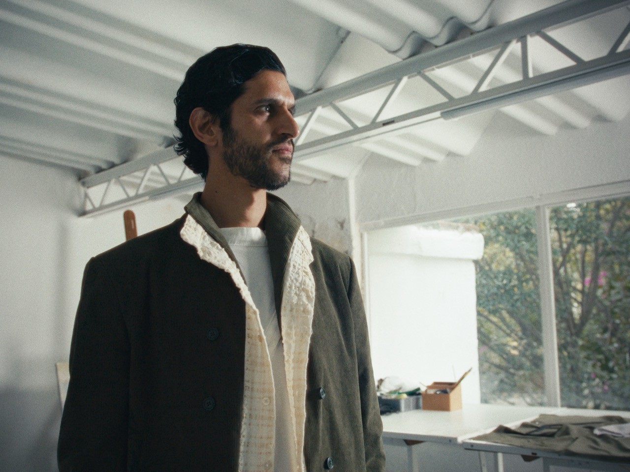 High-key menswear editorial still from the 'Kentish' fashion film for designer Camila Rubalcava. Photographed by Mexico City DP Mauricio Nader using a Blackmagic Pocket 6K G2 to capture texture and soft natural light in an industrial studio setting.