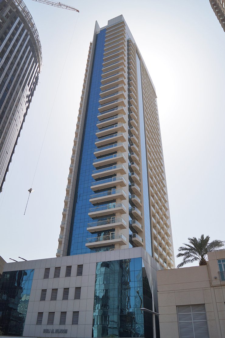 Modern glass facade of Burj Al Nujoom. Our team provides professional real estate services for buyers and tenants.