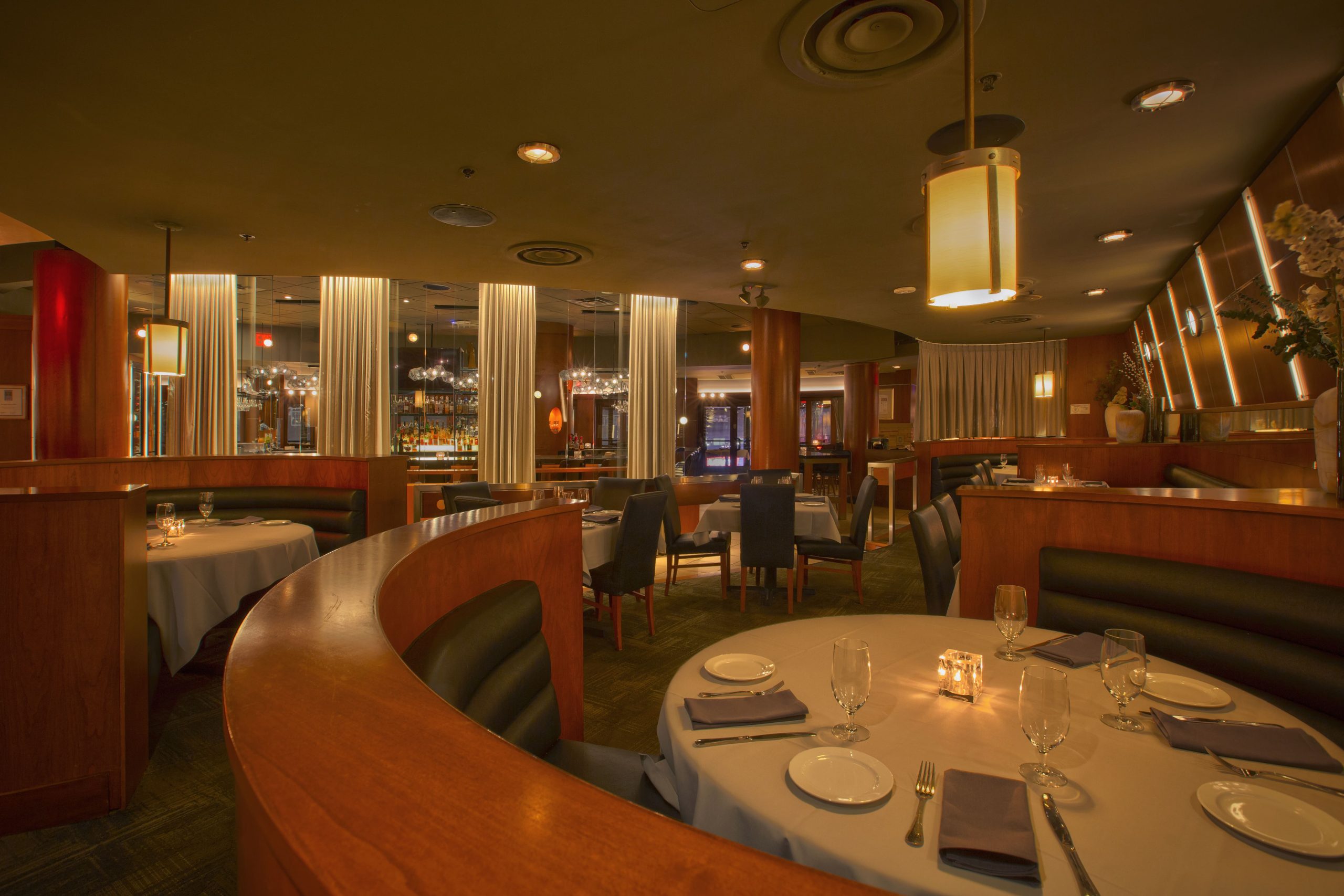 Curved leather booth around a round white-clothed table with a candle at Mitchell's Ocean Club