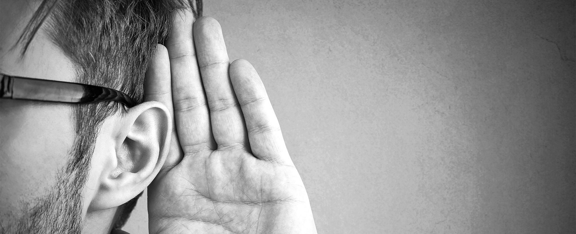 Close-up of a man holding hand next to ear to improve hearing