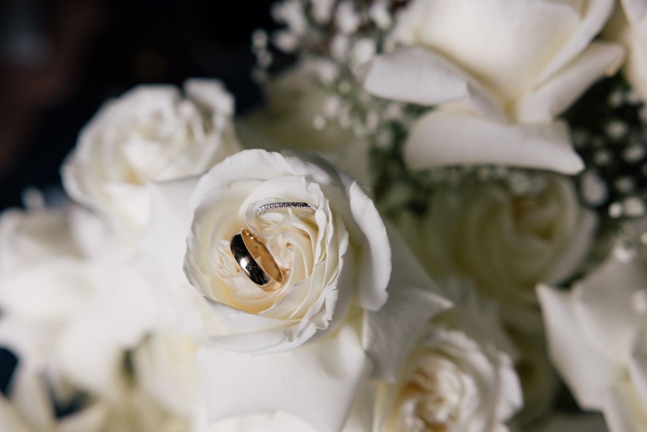 Fedi nuziali sulle rose bianche del bouquet da sposa al Castello di Tabiano