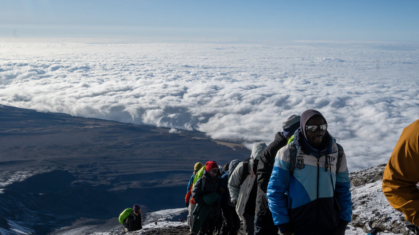 Team of Kilimanjaro porters ascending towards high camp with expedition loads