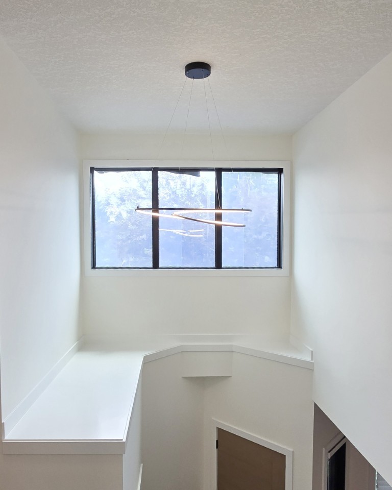 Image of Modern staircase landing with sleek lighting, large window, and minimalist interior design by KHD Homes.