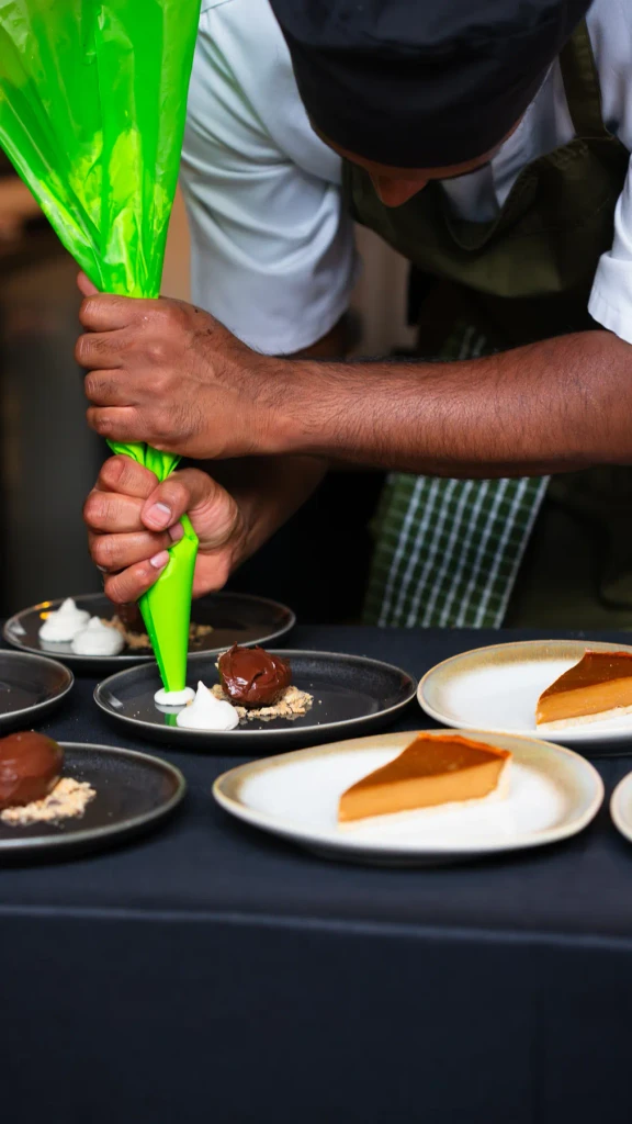 Josh piping cream onto desserts during service