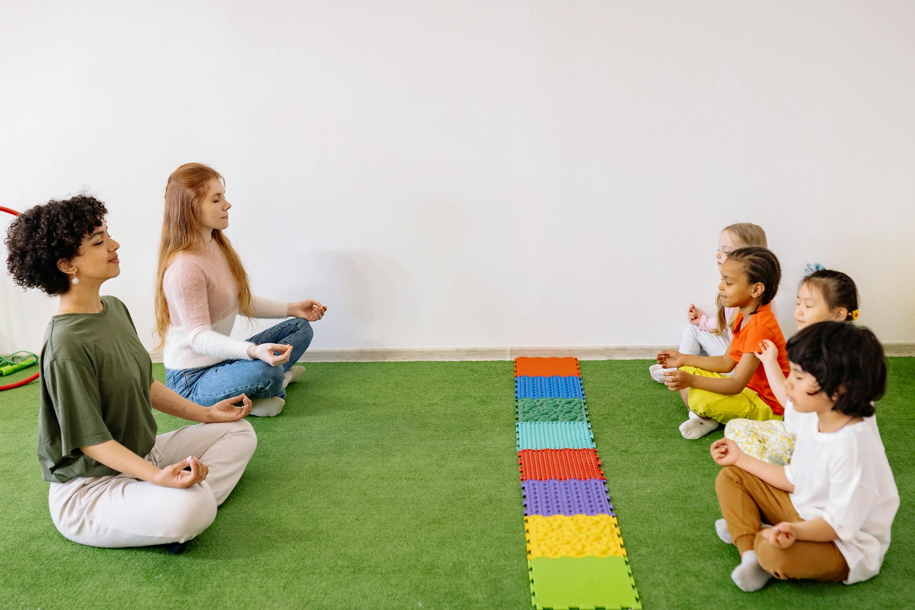 A group of diverse students sitting in a circle on a rug practicing deep breathing exercises for self-regulation.