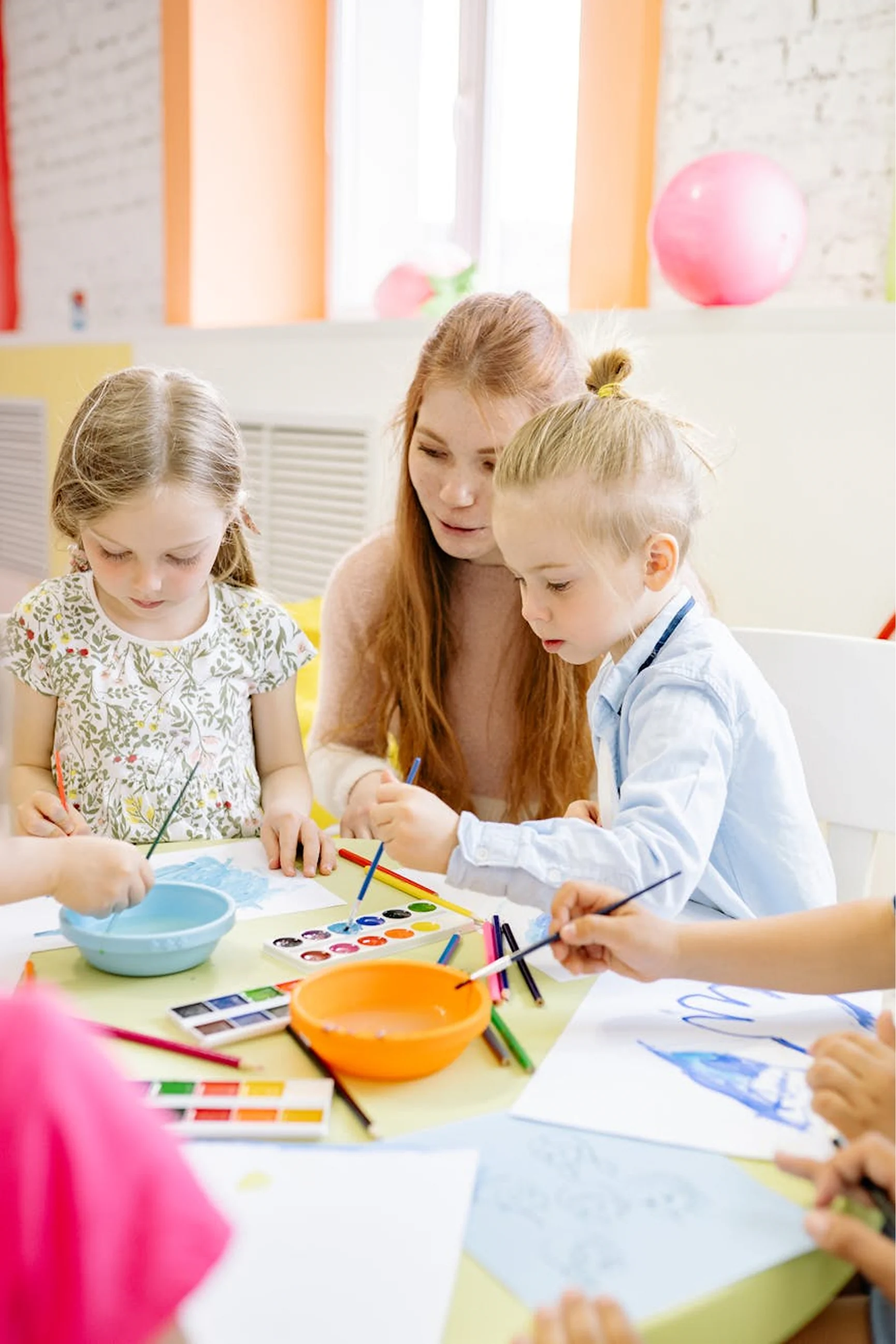 Preschool children painting and learning together with their teacher.