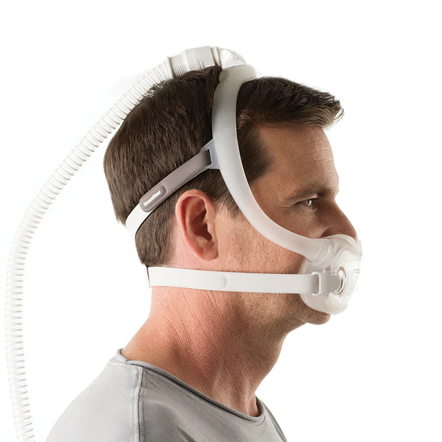 A side on photo of a man wearing a full mask CPAP machine
