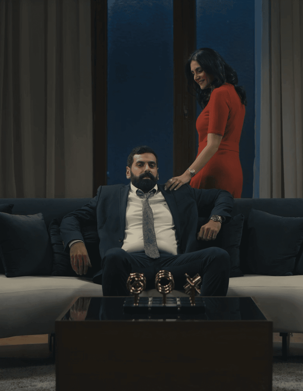 A modern office space with employees working at desks, plants, and a computer in the foreground.