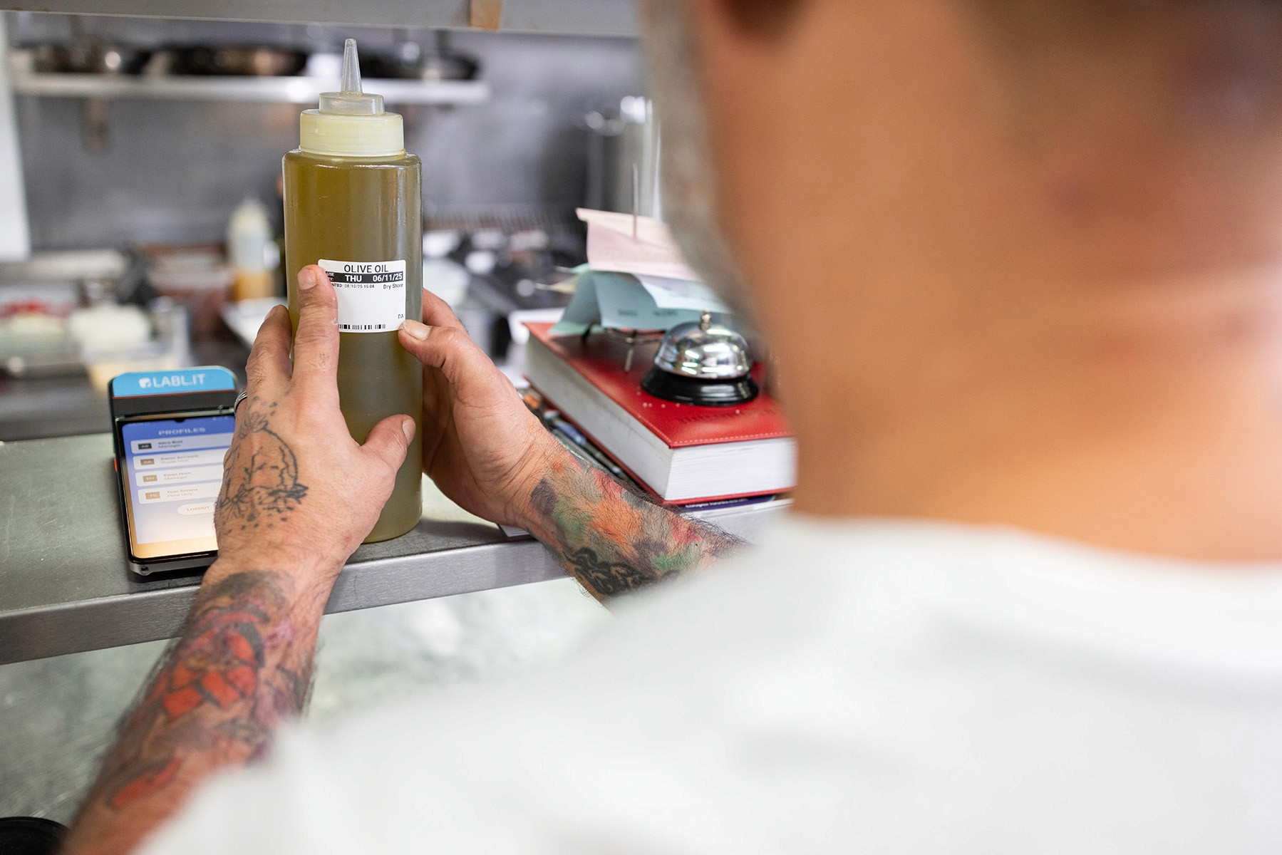 A chef sticking a food label onto a bottle of olive oil after printing it from a Labl.it device.