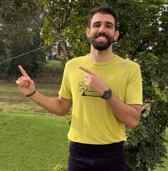 Treinador da pro elite sorrindo e apontando os dedos para o lado esquerdo