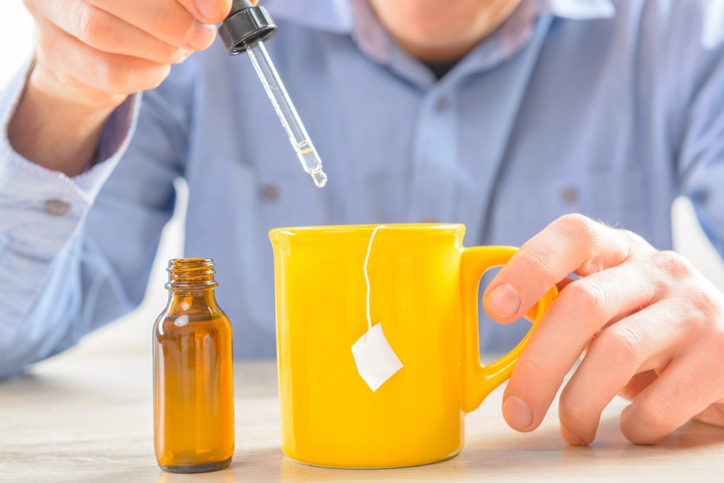 Sweetener fuild in hand with pipette into tea