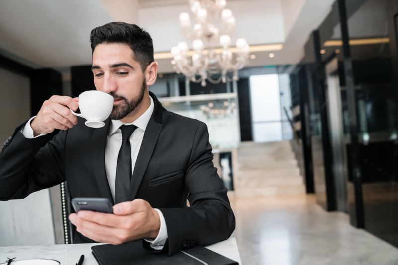 Person drinking coffee watching phone