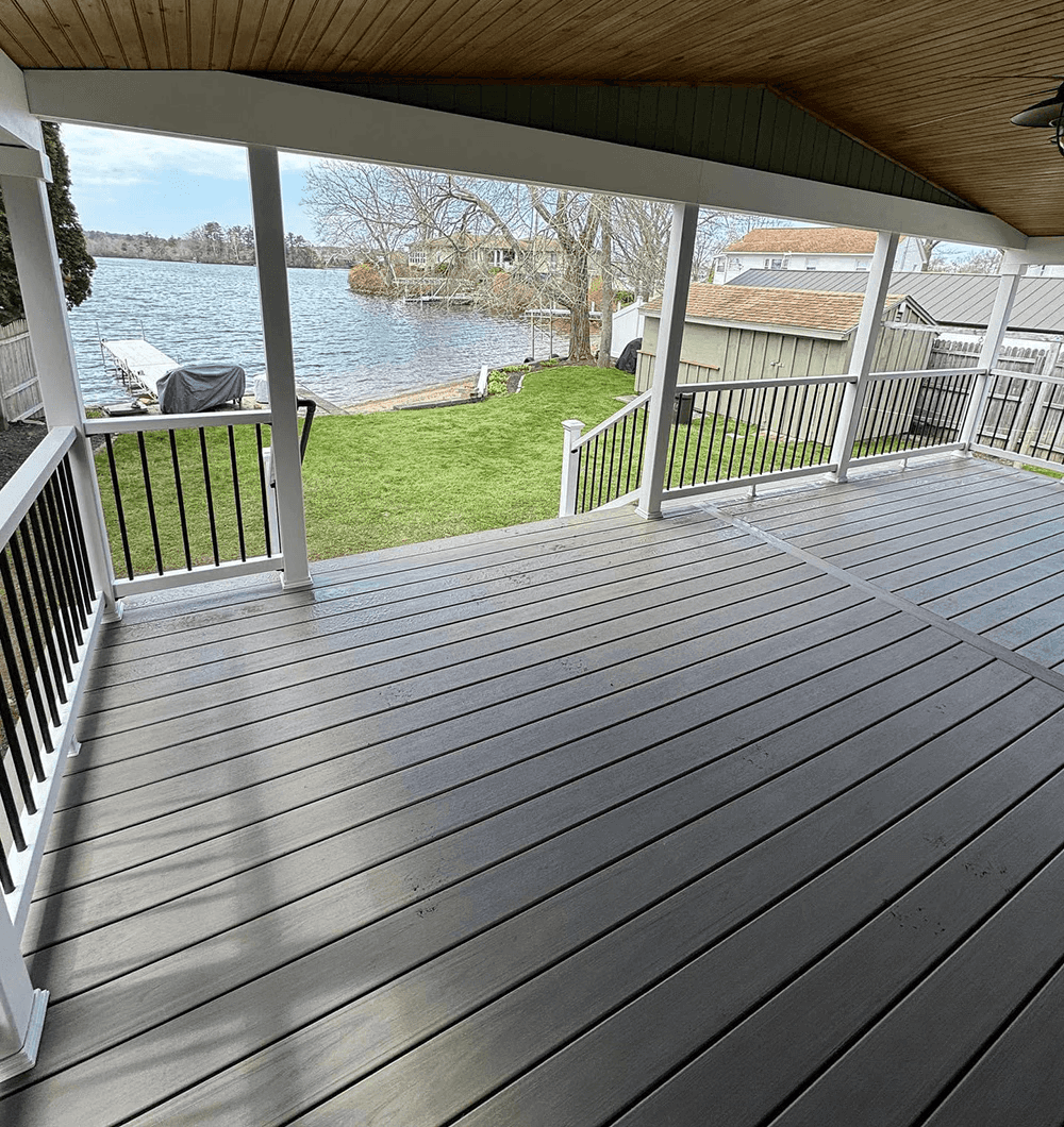 Grey Trex deck with white railings looking out at a lake with a dock