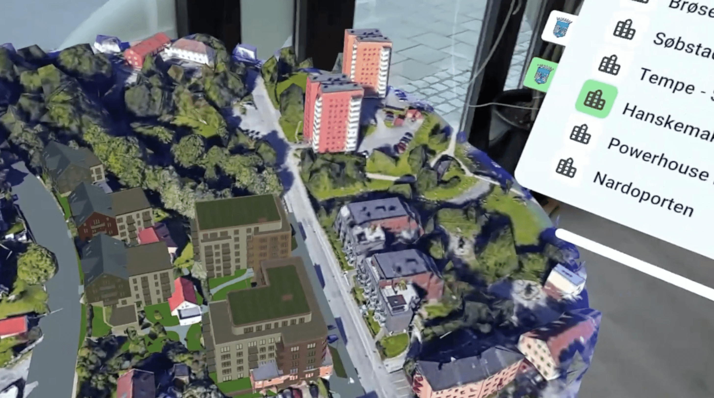 Viser en 3D-model af et byggeprojekt placeret på et 3D-kort.