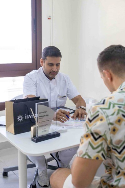 طبيب يسلم العميل تقويم الأسنان الشفاف الخاصة بإنهاء العلاج.