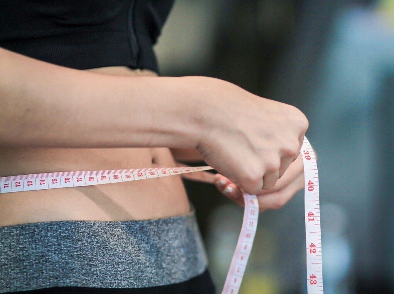woman using a tape measure to check her results from doing the best elliptical machine for weight loss over time
