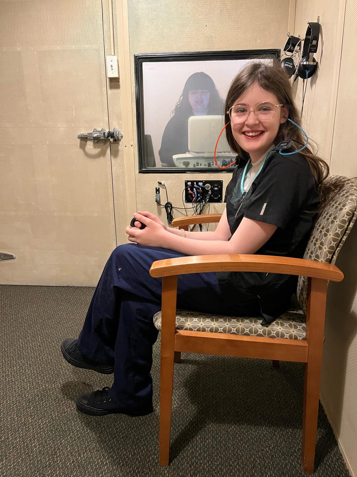 A woman smiles while gently styling the hair of a happy young girl in a bright, cheerful setting.
