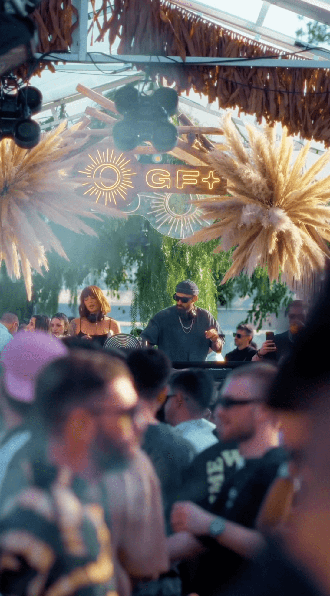 Smiling girl with closed eyes, wearing headphones and relaxing on a hanging chair, surrounded by green plants