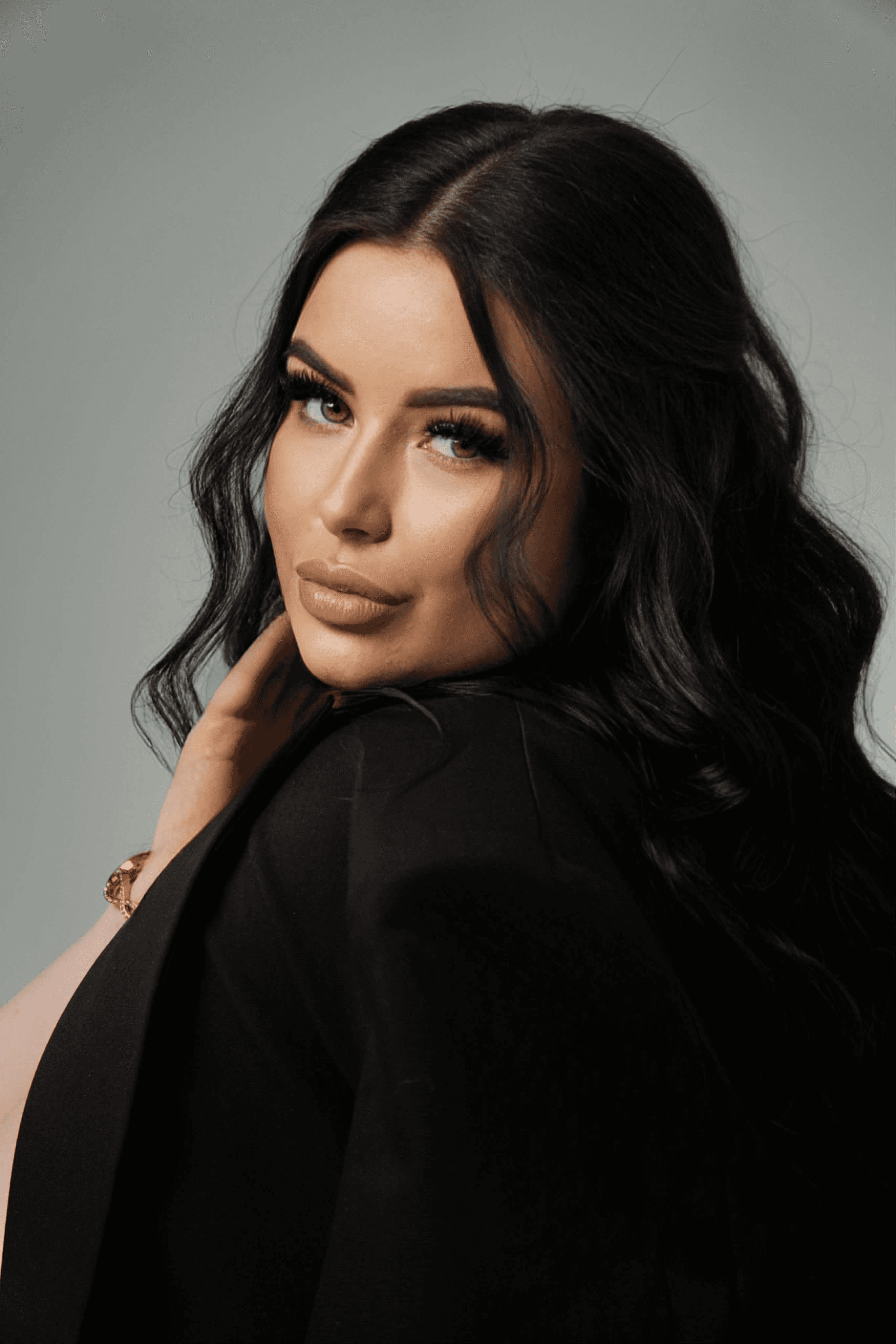 A person with shoulder-length blonde hair wearing a black newsboy cap and a black sweater.