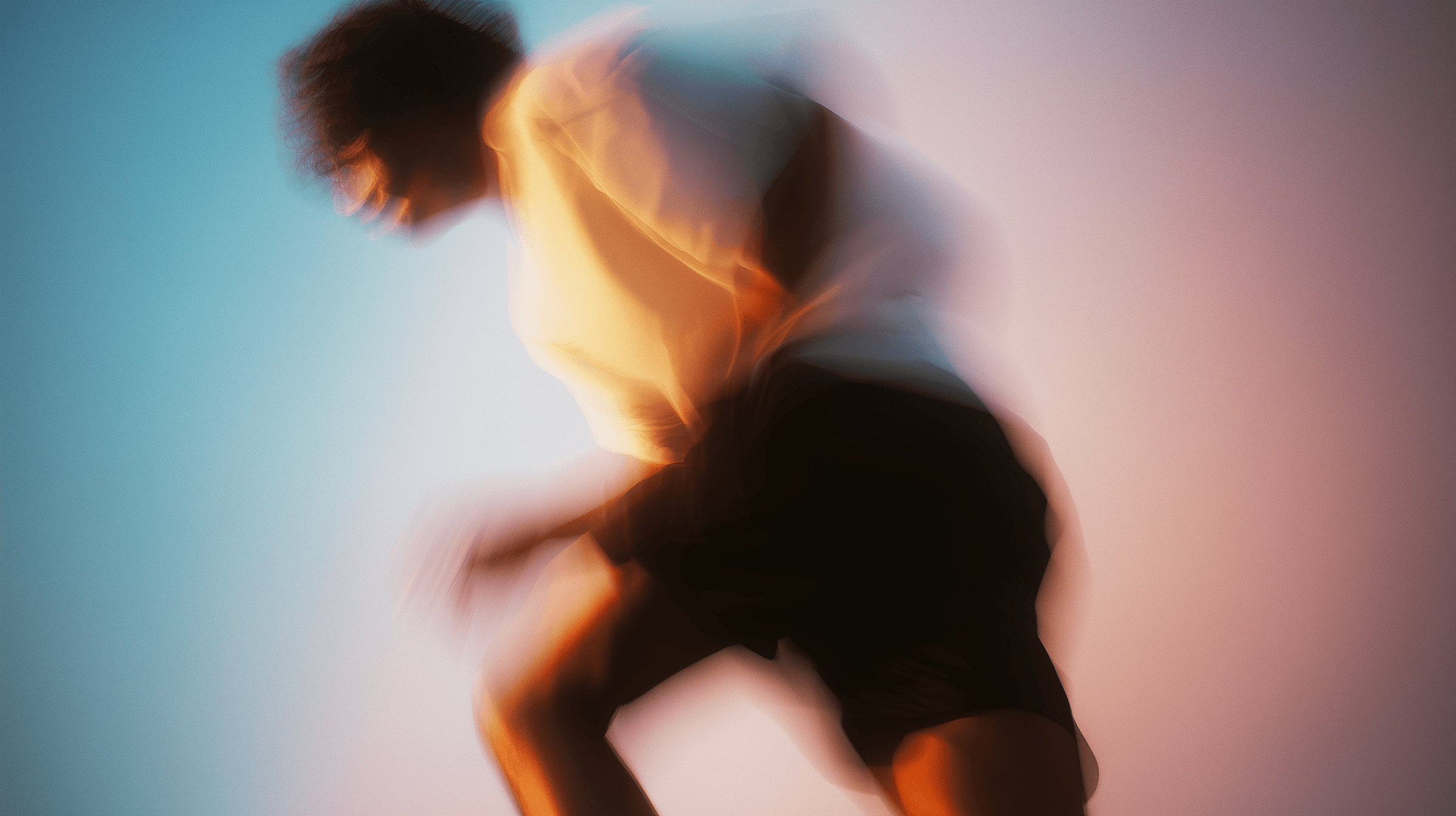 Dancer captured mid-movement against a teal and blue background.