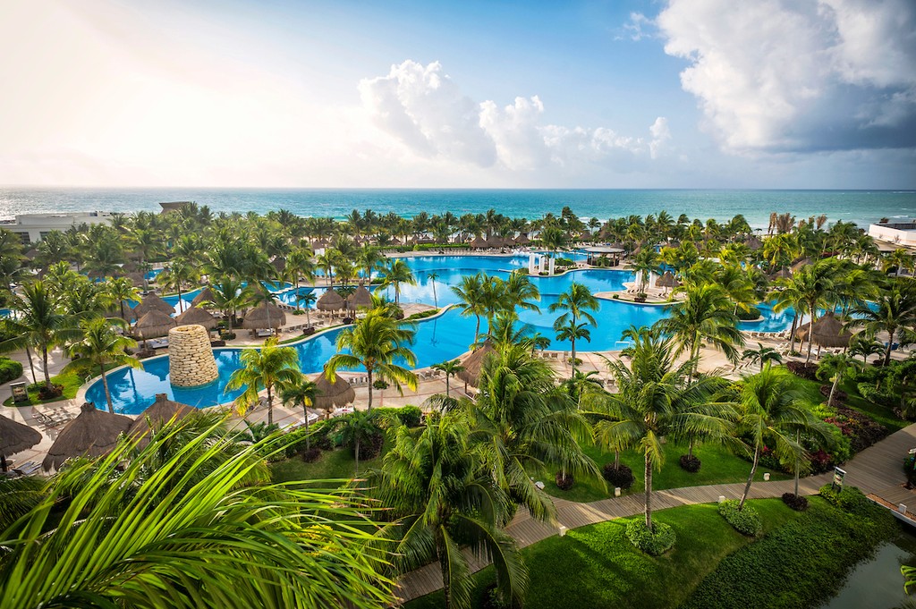 Couple standing on a balcony with binoculars in hand looking out over the ocean