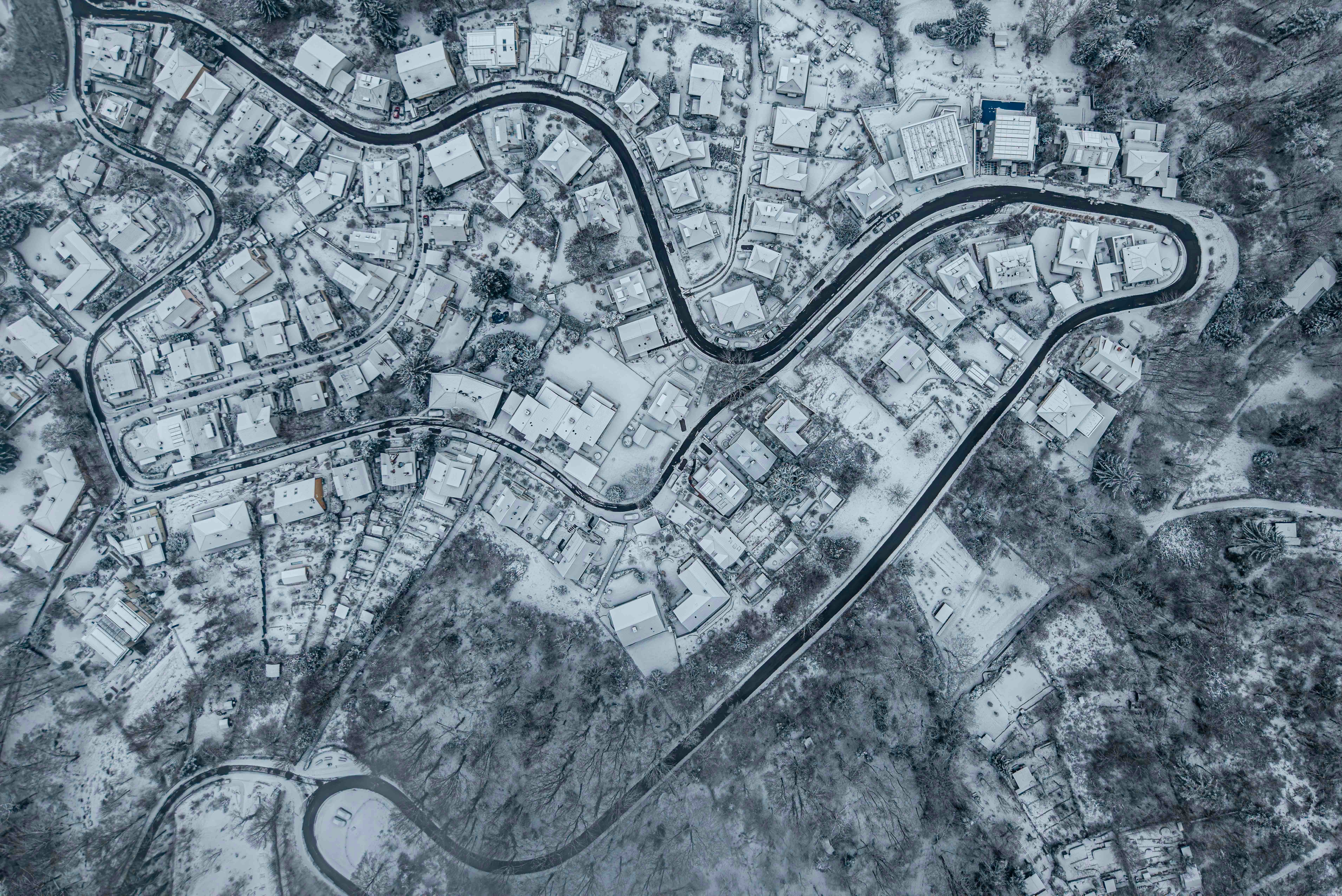 Aerial view of a snow-covered village with winding roads