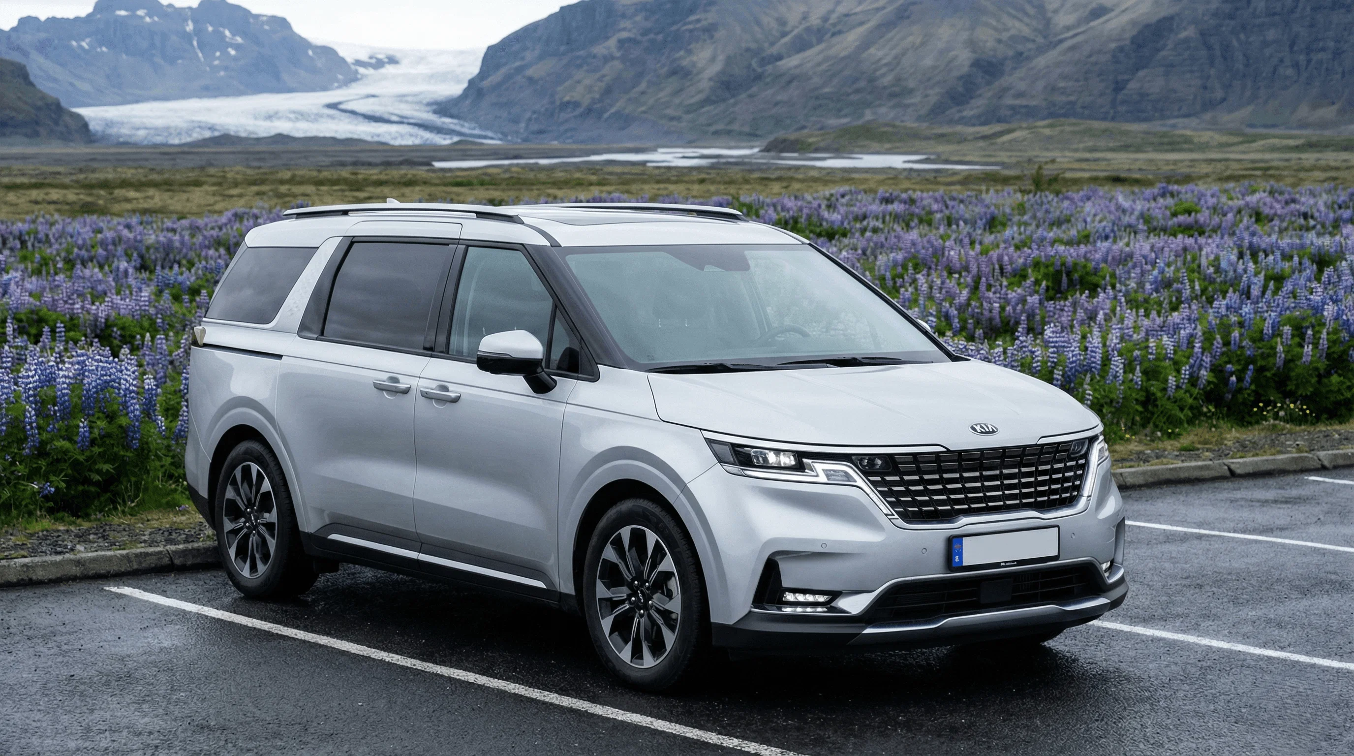 A silver Kia SUV driving on an asphalt road with dark mountains and dramatic clouds in the distance