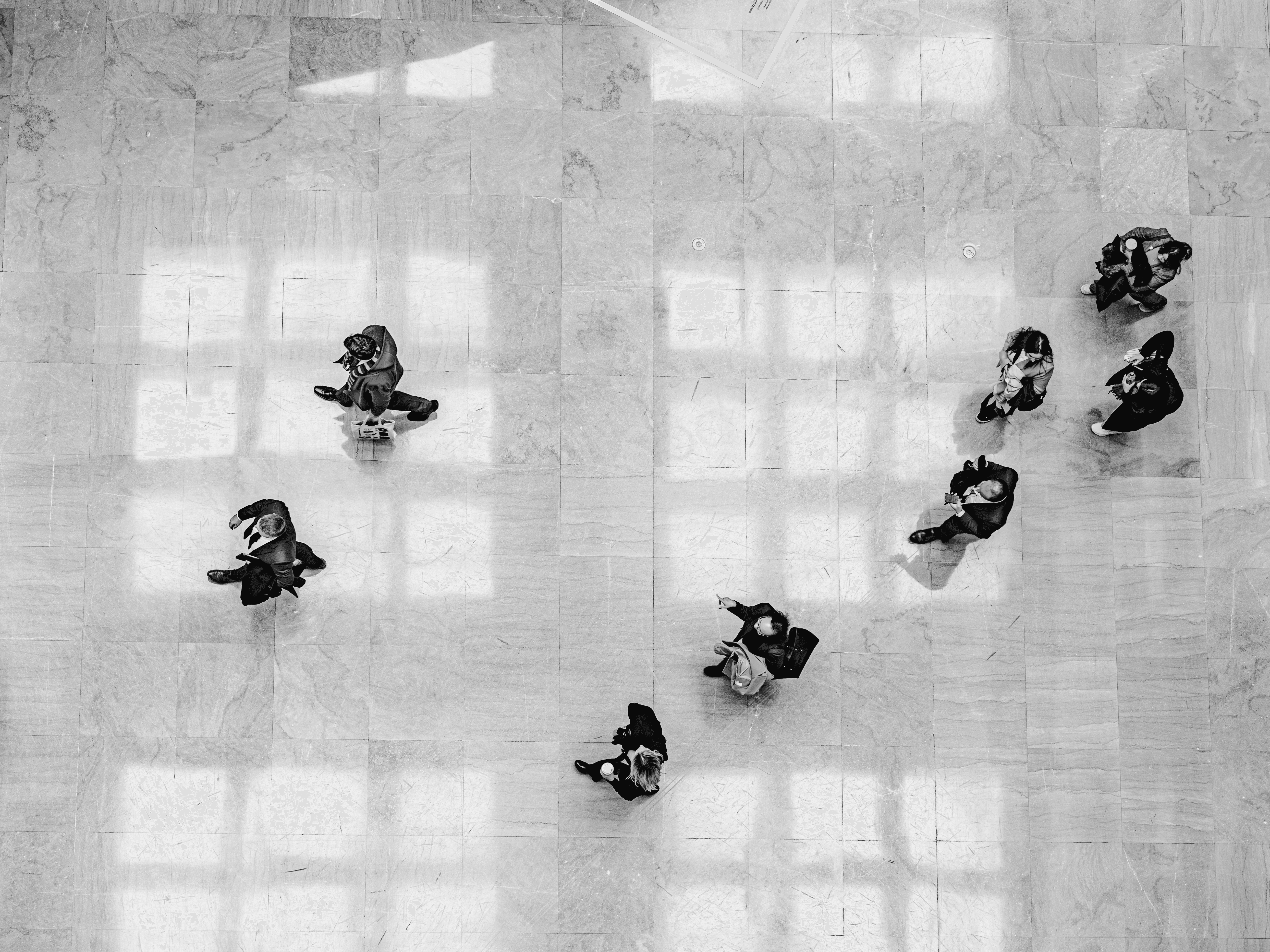 Several people walk across a tiled floor.