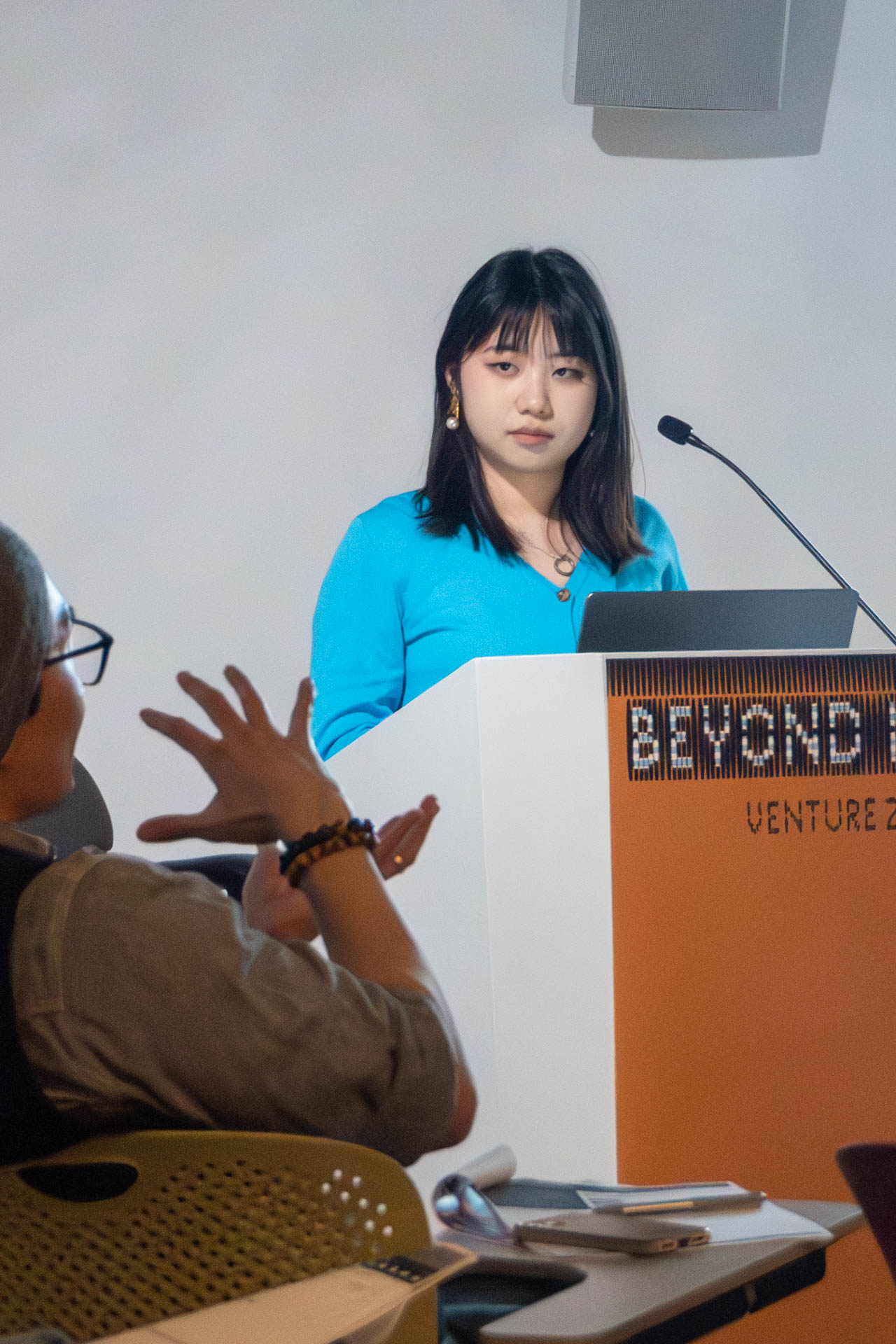 A lady at the podium giving a presentation to a class.