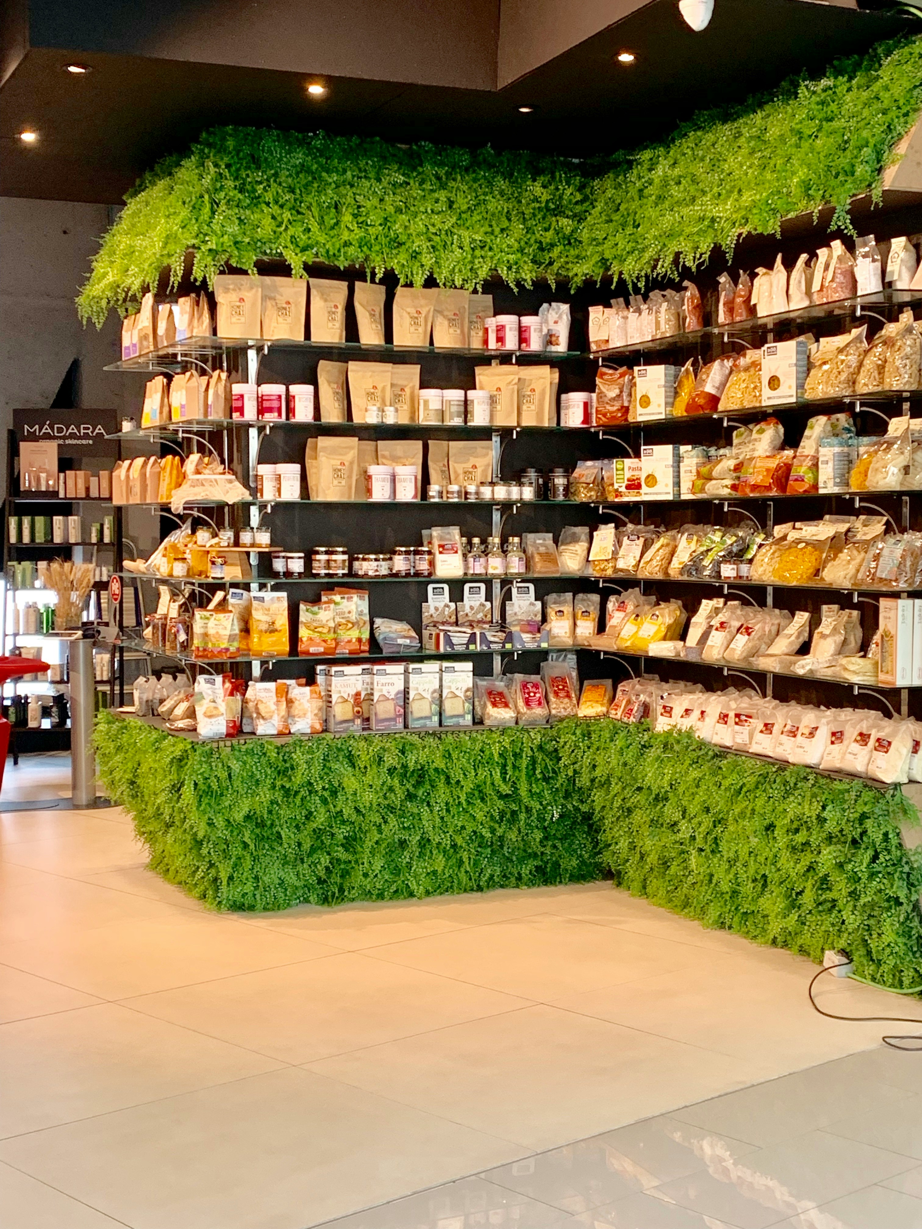 A grocery store display featuring natural groceries such as fresh fruits, vegetables, whole grains, and organic products arranged neatly on wooden shelves.