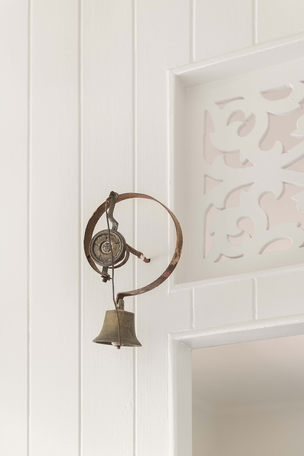 Detail of heritage timber fretwork and wall-mounted light at The Stables, referencing the home’s original character within the contemporary renovation.