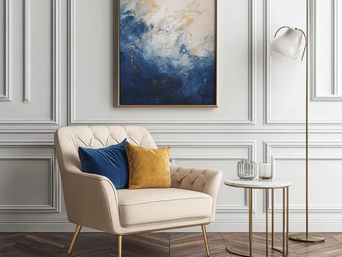 Elegant seating area with a cream tufted armchair, blue and mustard cushions, gold floor lamp, and abstract wall art