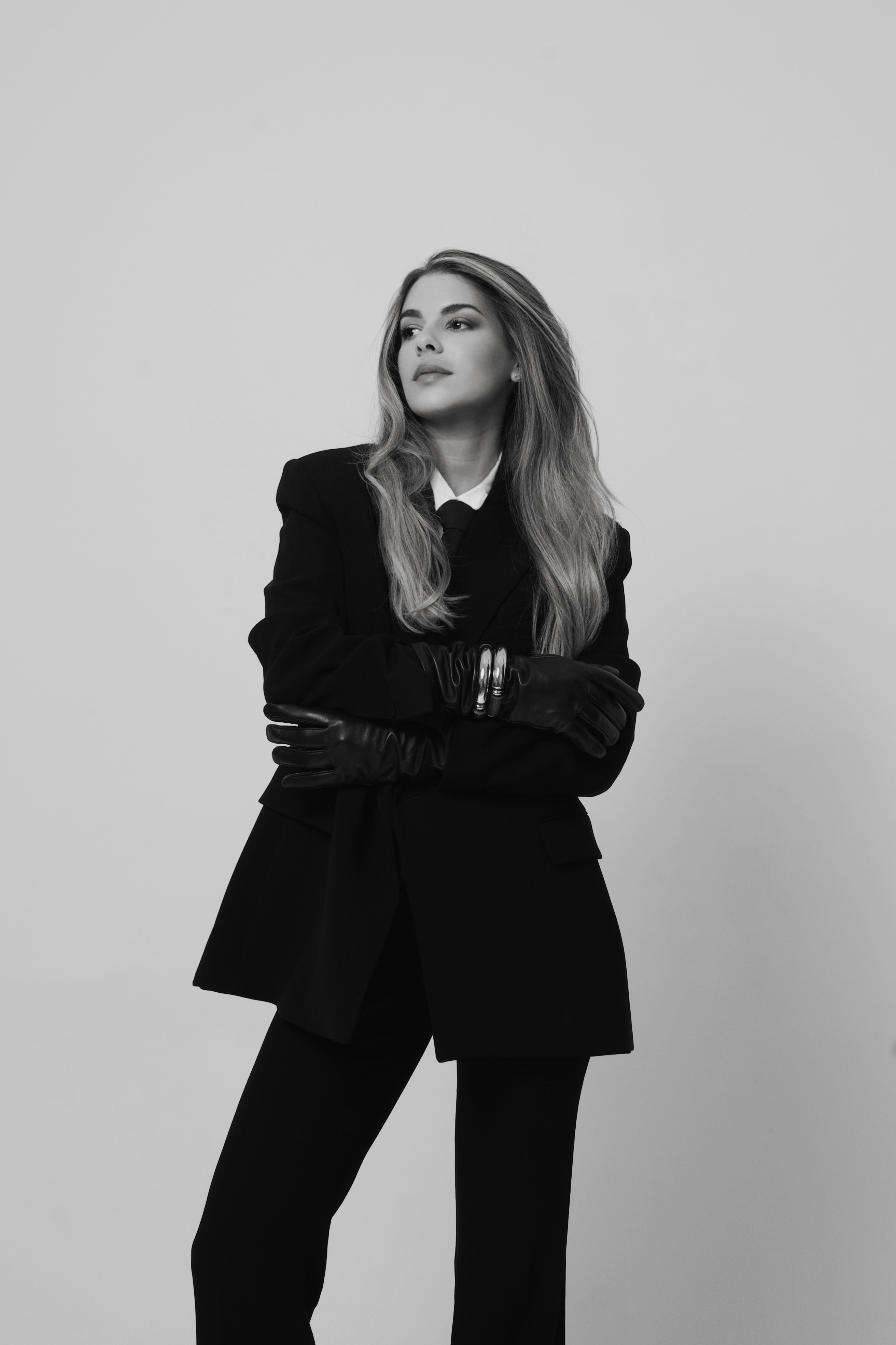 A softly lit hallway with a series of arched doorways, warm-toned walls, and wood flooring leading toward a seating area with neutral furniture.