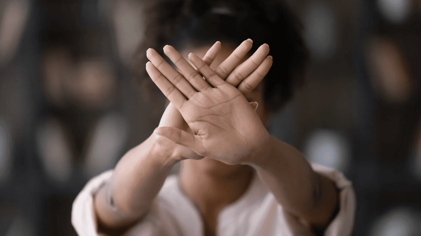 Person holding crossed hands in front of face as a stop gesture, symbolising breaking away from outdated Amazon PPC habits and embracing automated, efficient ad management systems to prevent wasted spend.