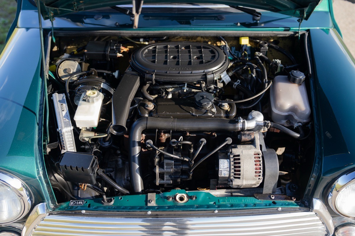 Close-up of a car engine under the hood, showcasing various components and a teal exterior.