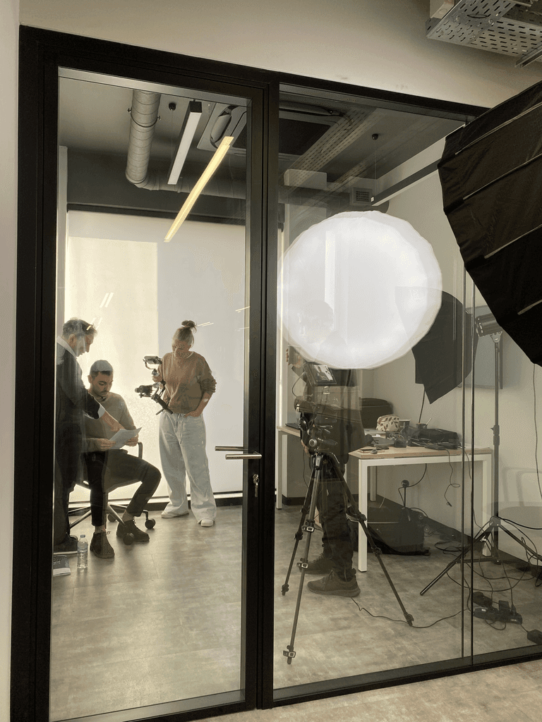 Behind-the-scenes view of a video production team preparing a speaker in a studio with cameras and lighting equipment