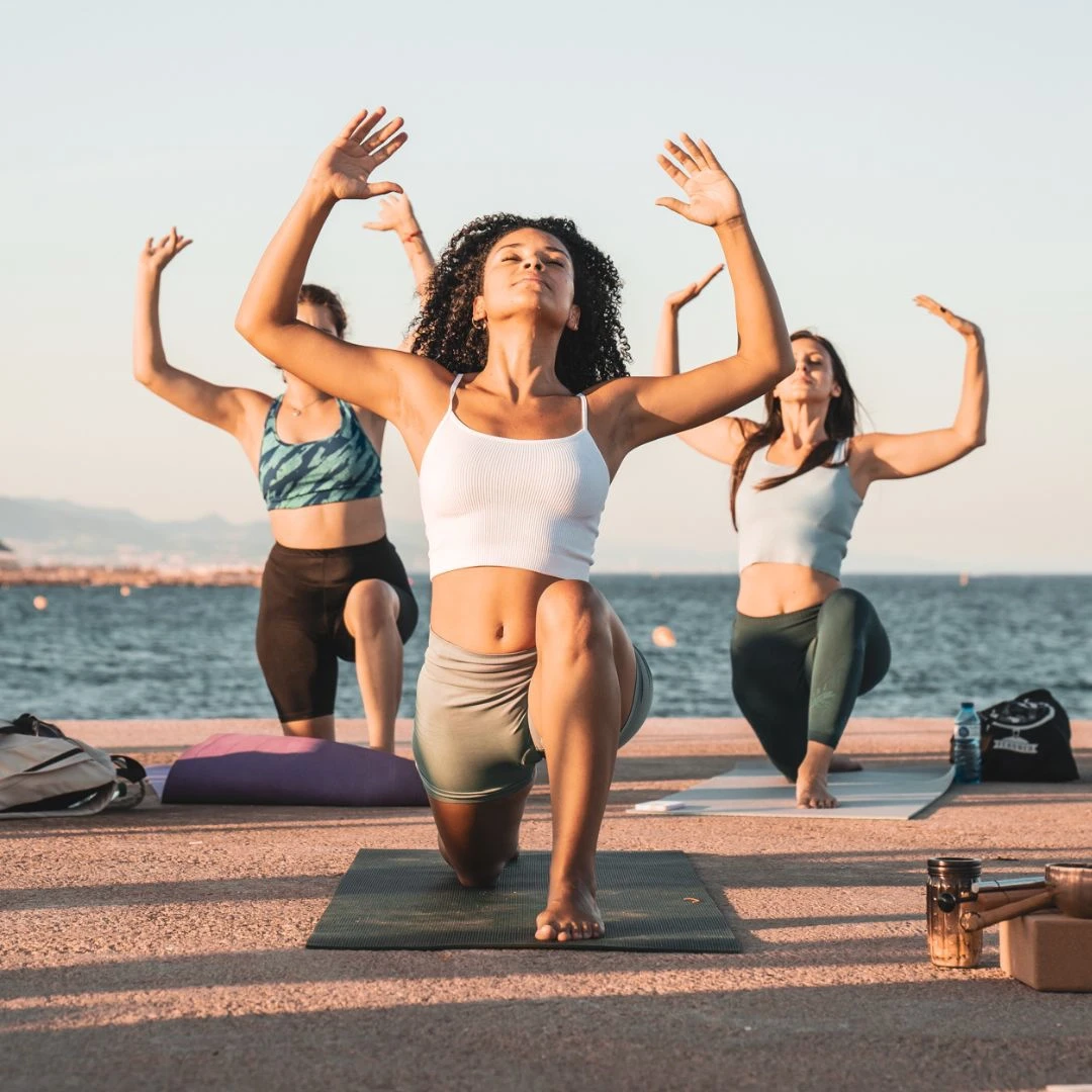 Duby practising yoga at the beach with 2 girls