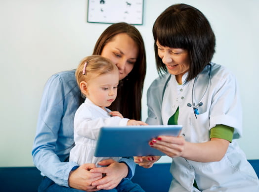 Сімейний лікар показує дівчинці щось на планшеті