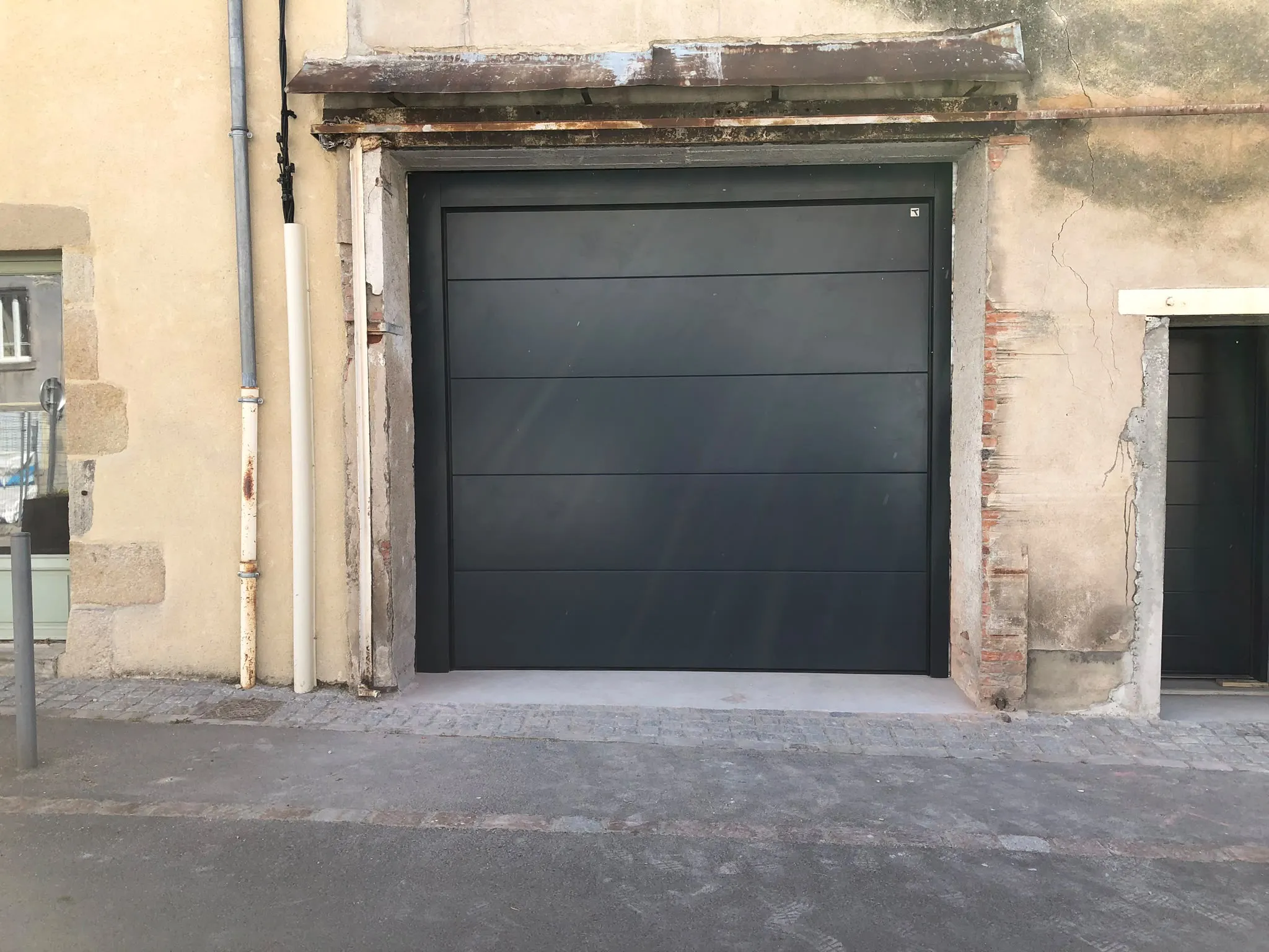 Porte de garage sombre vue depuis l’allée — AFermetures