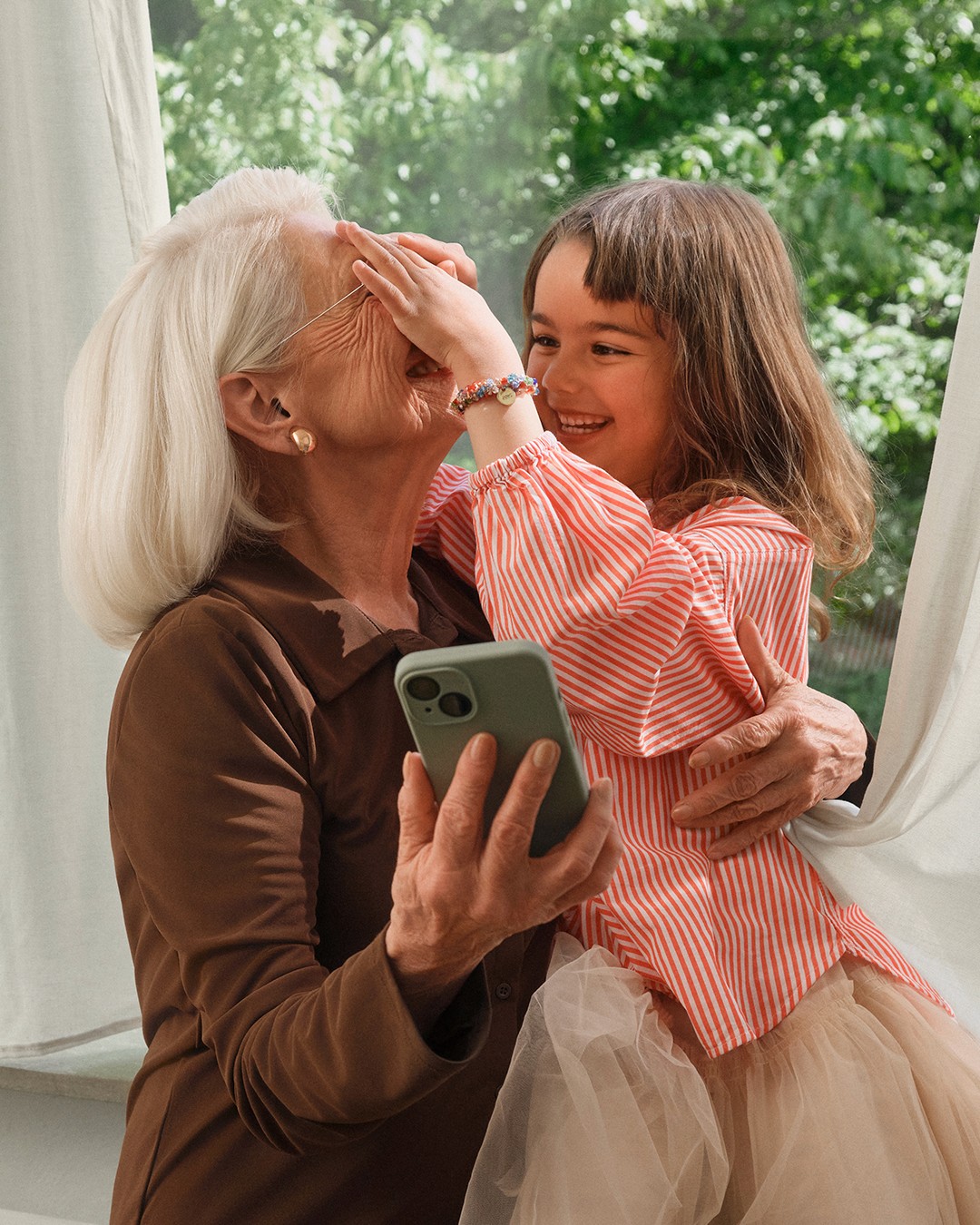 Grandmother and granddaughter sharing a joyful moment in Fielmann’s hearing care campaign.