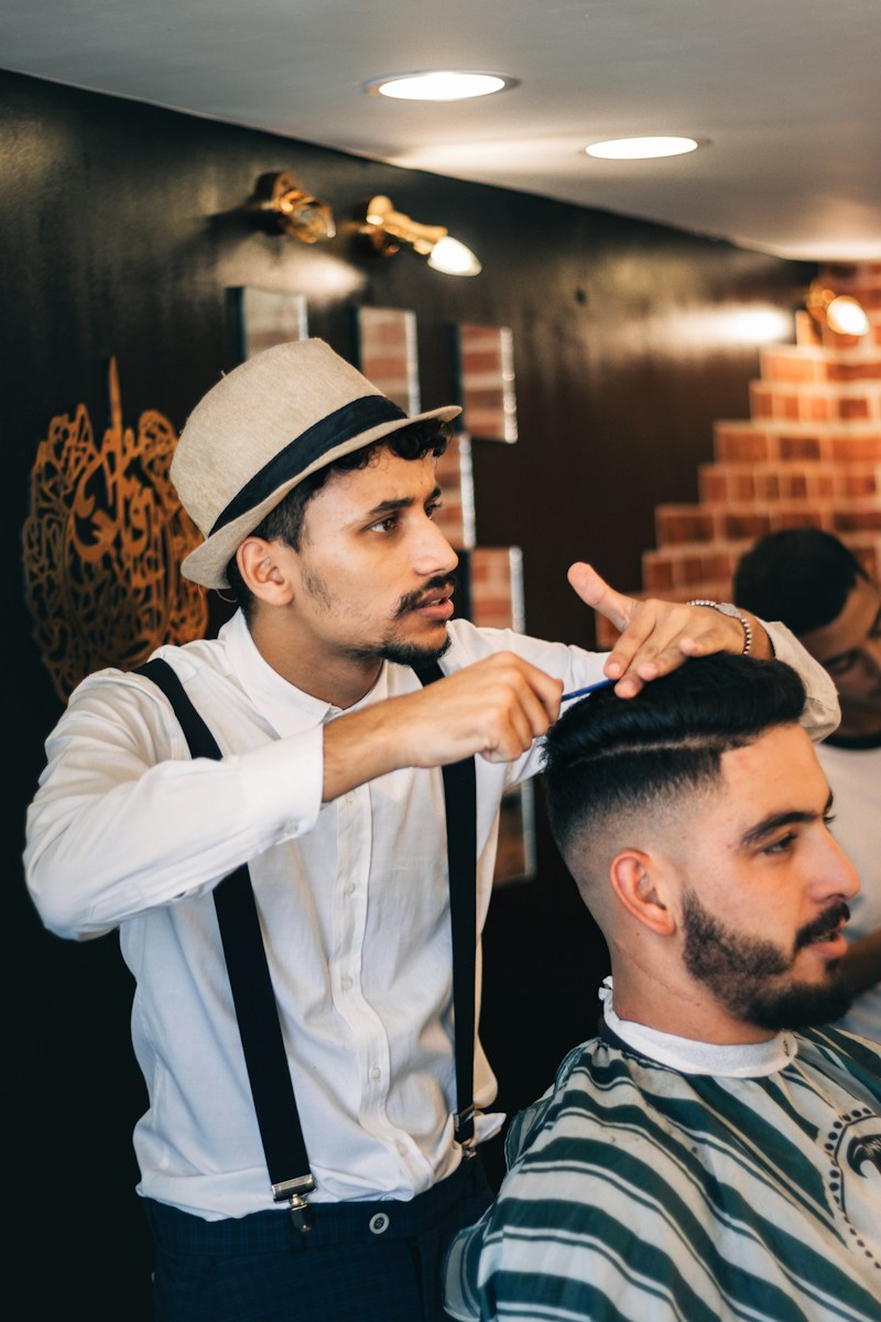 A barber shaping a customer's beard