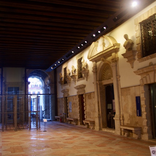 历史建筑内部一条宽敞的走廊，配有拱形门洞、装饰性的石质建筑细节和雕像。
