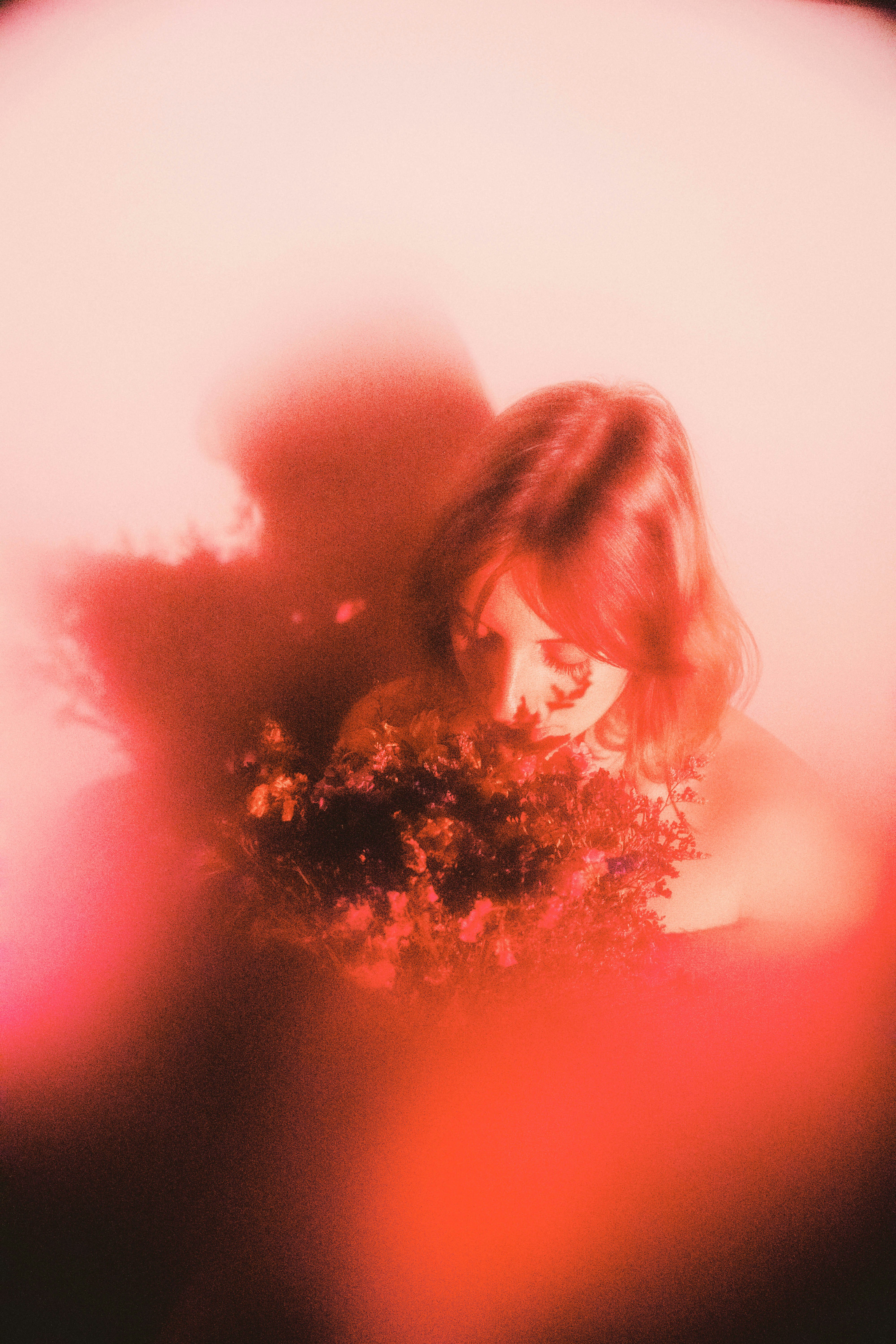 Woman with flowers amidst red hues.