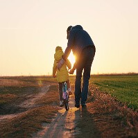 A parent with their child on a bike in a field