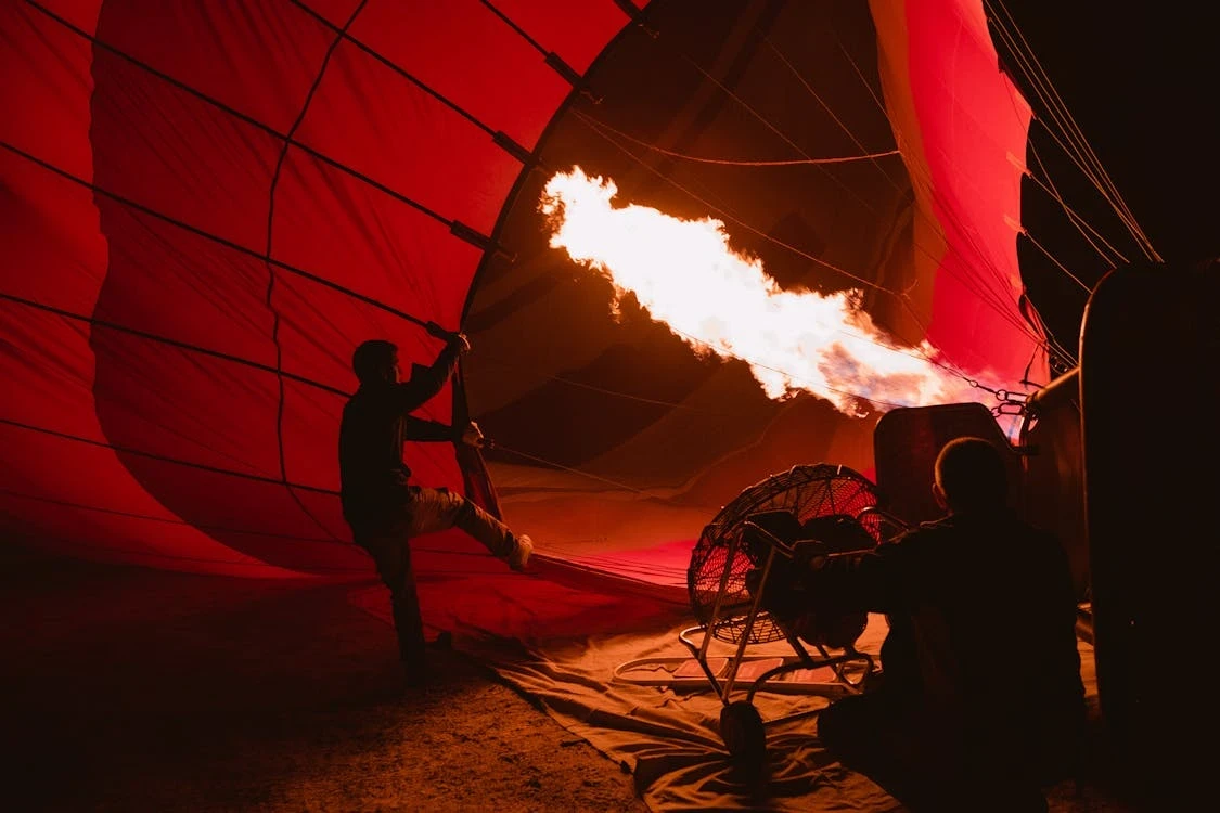 Two people lighting the hot air balloon, preparing for take off.