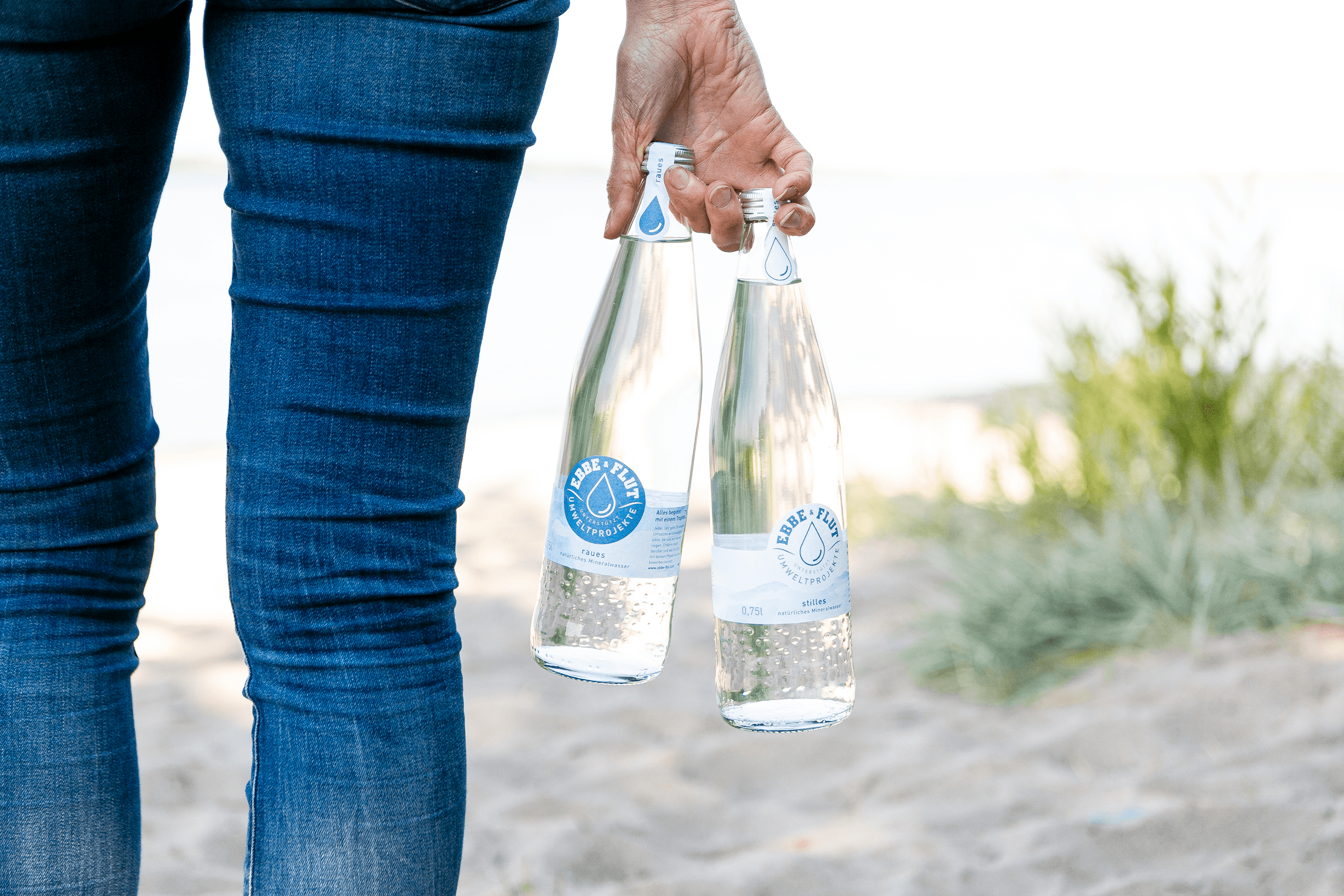 Person holding two glass bottles of sparkling water